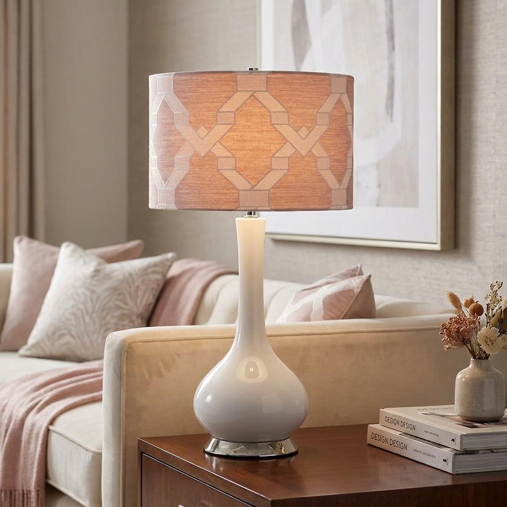 Milo table lamp with a white ceramic teardrop base and a pink geometric pattern shade on a wooden side table.