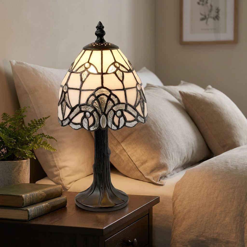 Tiffany style bedside lamp with a white glass shade and tree-trunk base, placed on a nightstand in a bedroom.