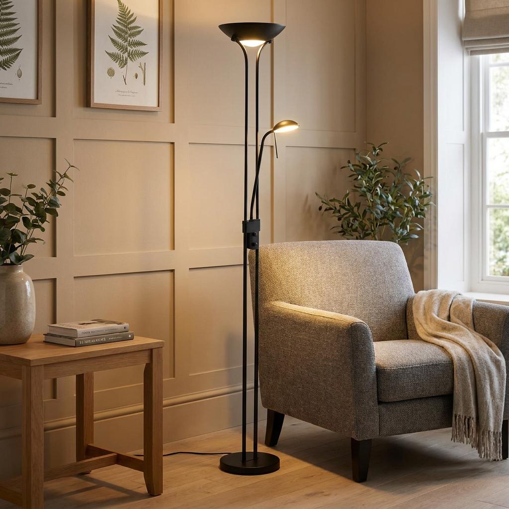 Slim black LED floor lamp with dual light sources illuminating a cozy living room nook with a grey armchair.