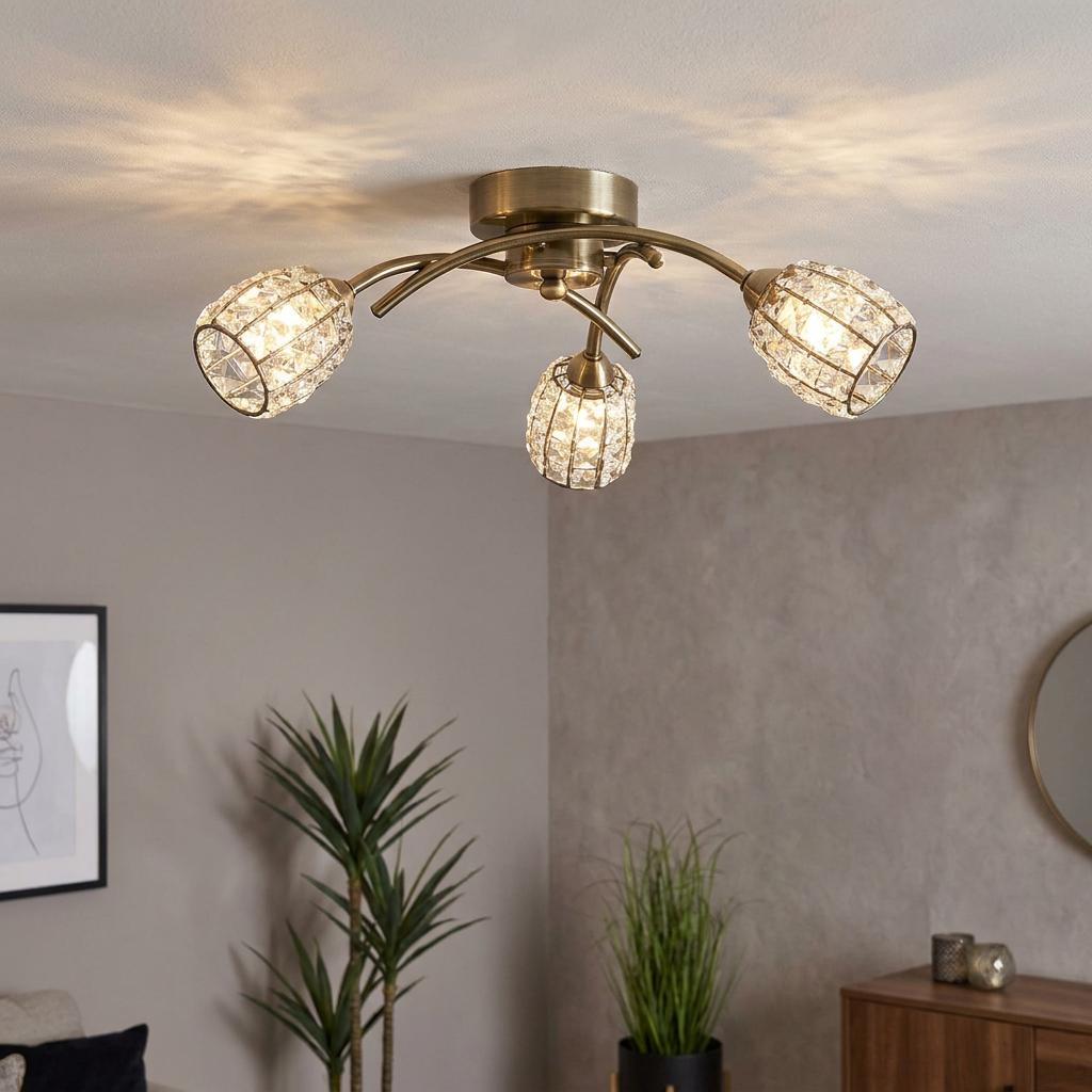 Antique brass 3-light flush ceiling fixture with crystal-beaded mesh shades, illuminated in a modern living room.
