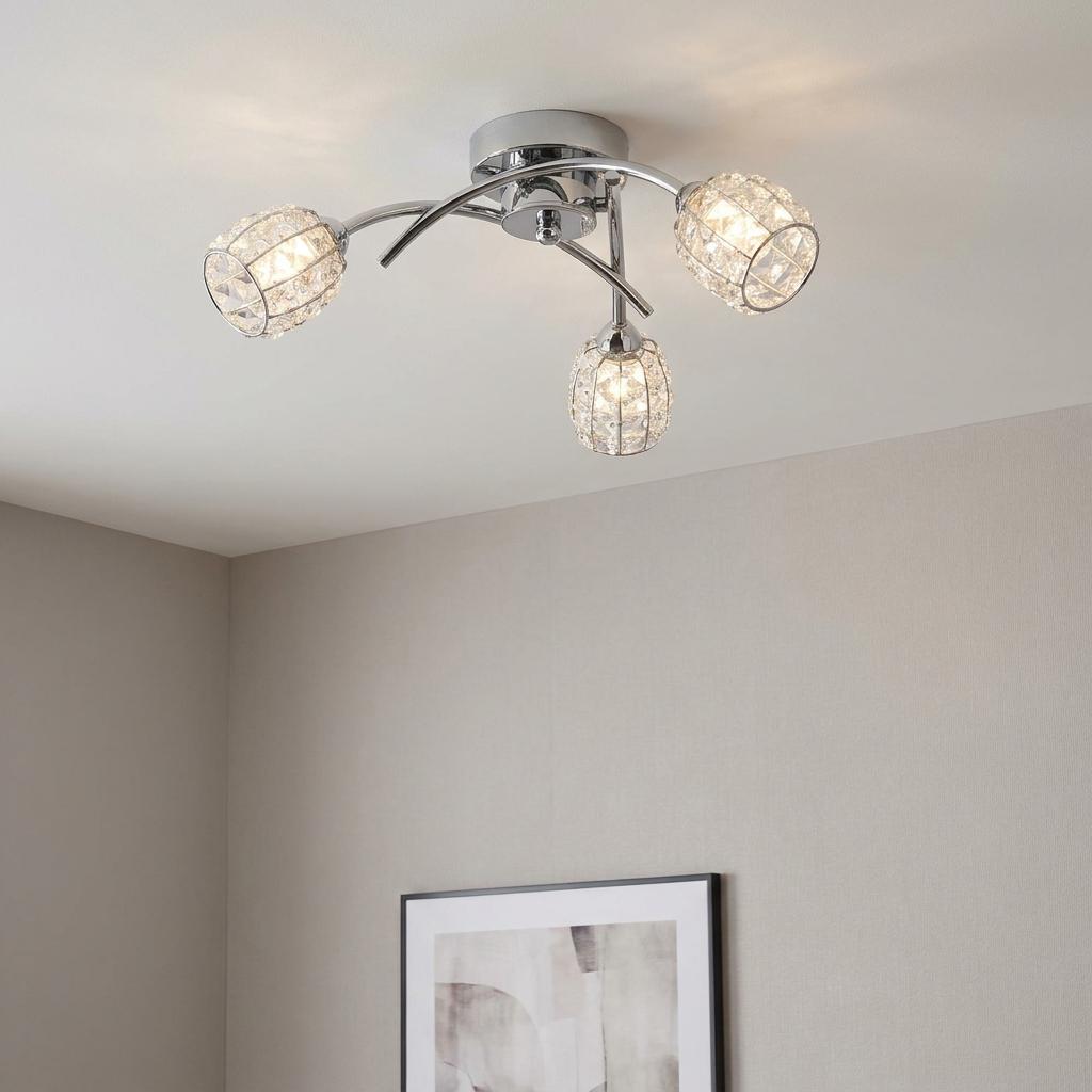 Modern three-light chrome ceiling fixture with illuminated crystal shades mounted on a plain ceiling.