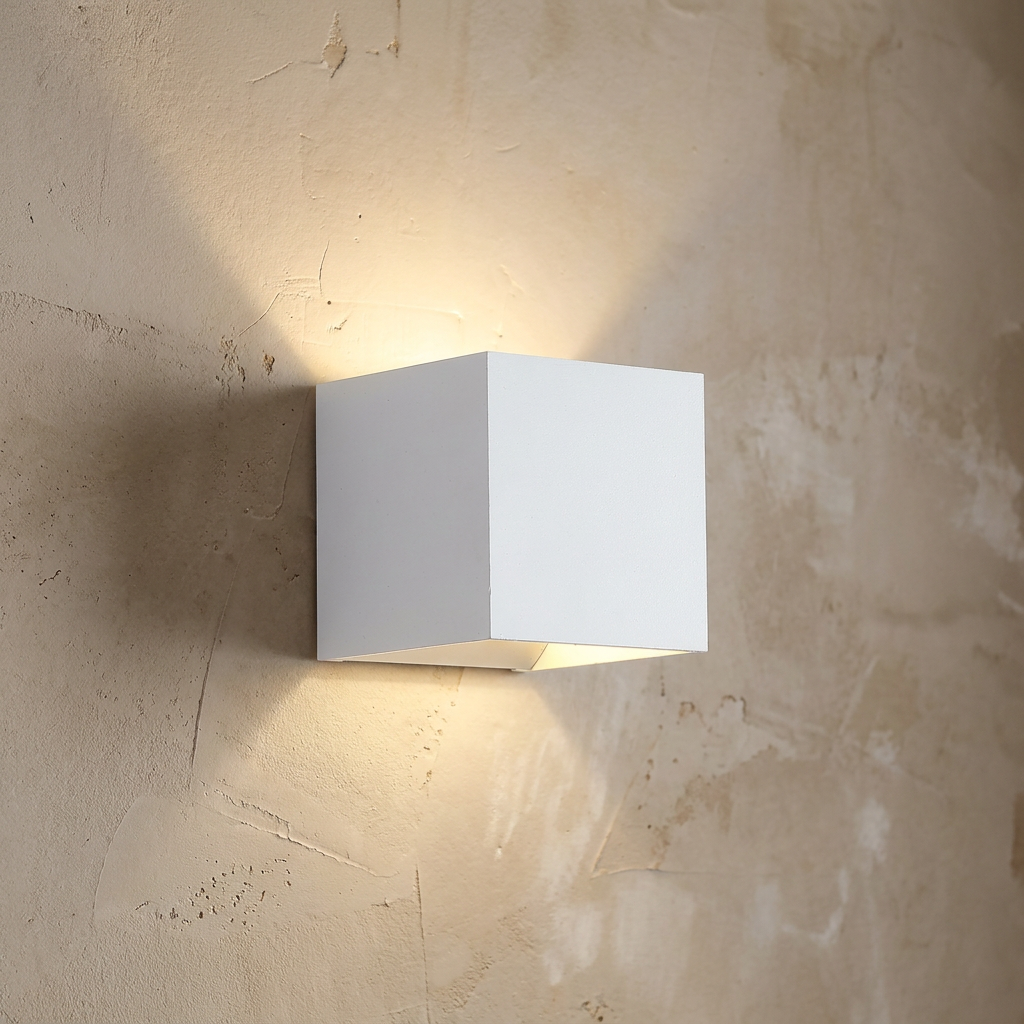 Modern white cube wall light casting an up and down warm glow on a textured plaster wall.