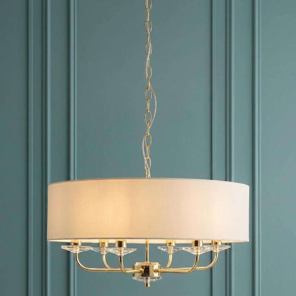 Nixon 6 Light Brass and Glass Ceiling Pendant with white shade against a teal panelled wall.