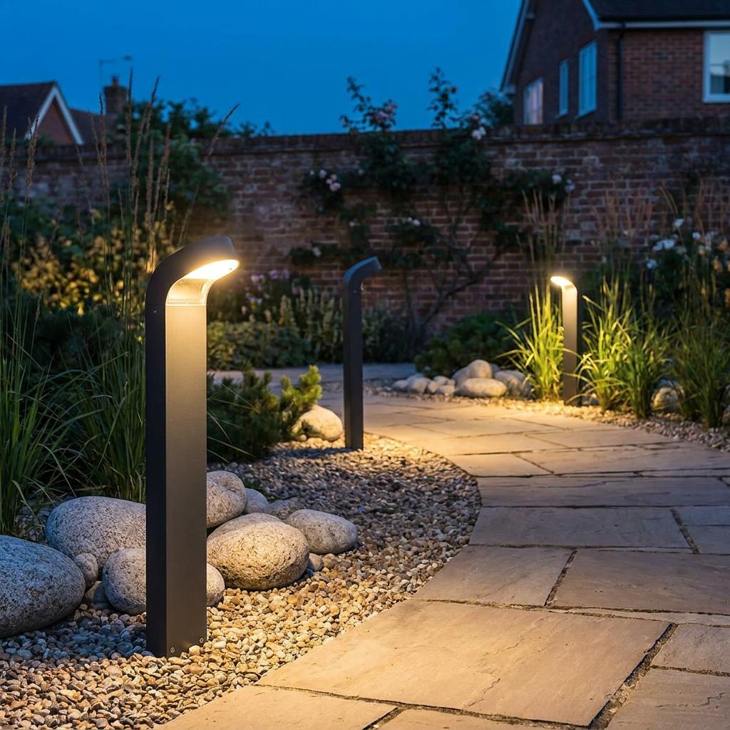 Three Norlys Molde graphite outdoor bollard lights illuminating a stone garden path at twilight.