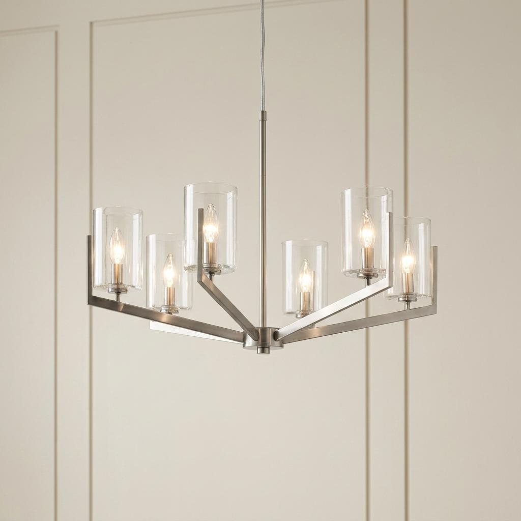Nye 6-light pewter chandelier with clear glass cylinder shades against a neutral paneled wall.