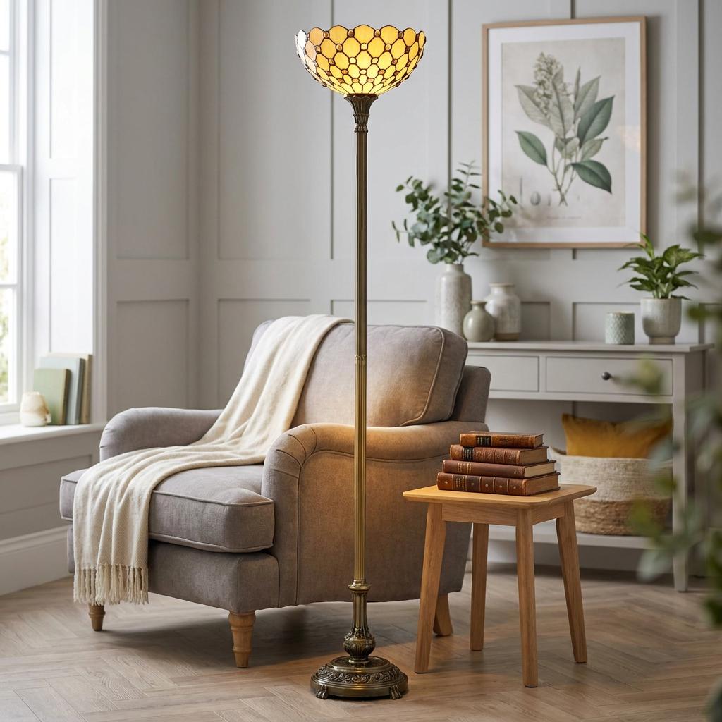 Tiffany jewel torchiere floor lamp with a honey glass shade beside a grey armchair in a living room.