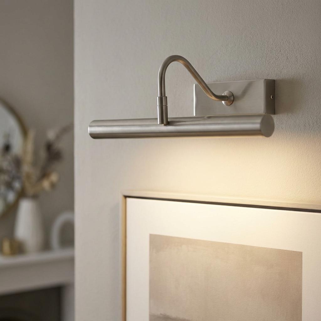Antique chrome LED picture light mounted on a wall, illuminating a framed artwork below.