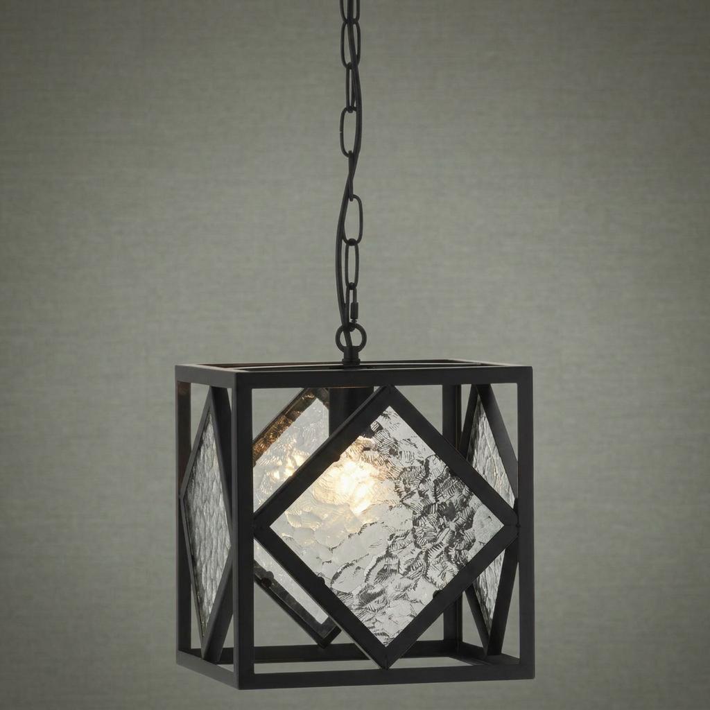 Black geometric lantern pendant with mottled glass panels hanging from a chain, illuminated against a neutral wall.