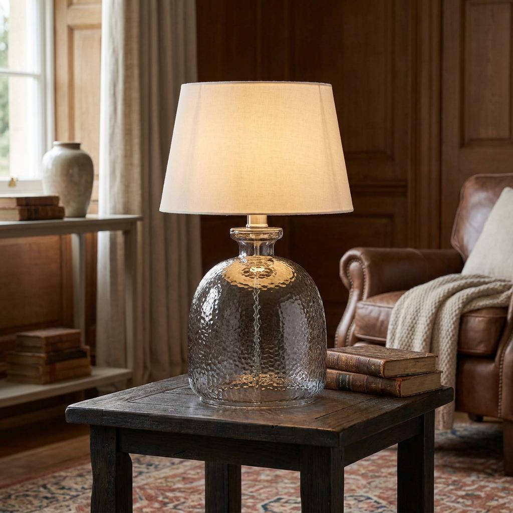 Oaks Lighting Arno Smoked Glass Table Lamp with a textured base and cream shade on a wooden side table in a cozy room.