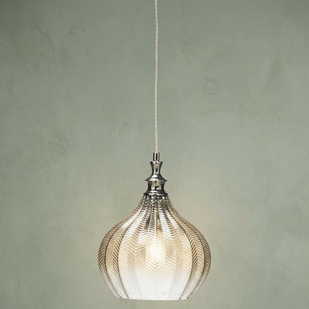 Cognac textured glass pendant light with chrome accents hanging against a muted green background.