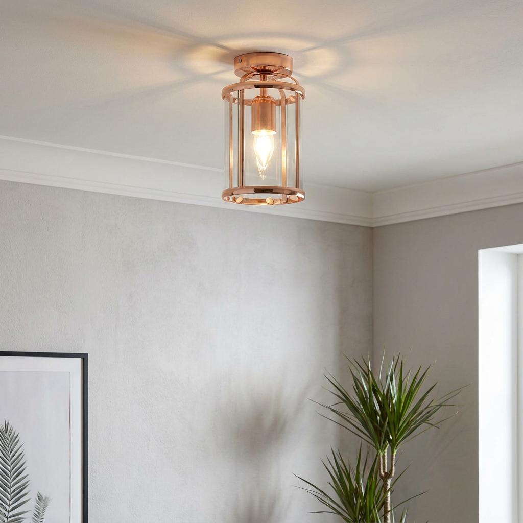 Copper ceiling flush light with a cylindrical glass shade and polished metal frame, illuminated on a plain ceiling.