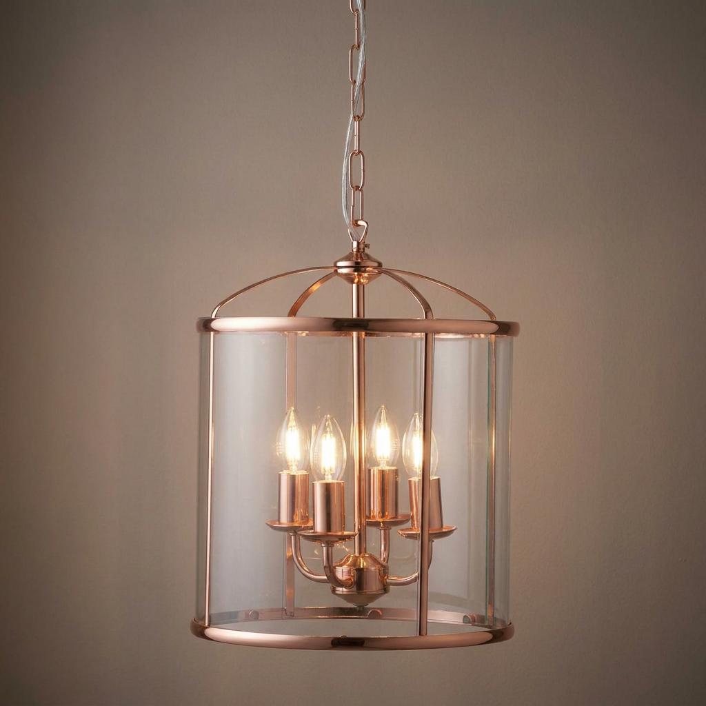Copper ceiling lantern with glass panels and four candle-style lights, hanging from a chain against a neutral background.