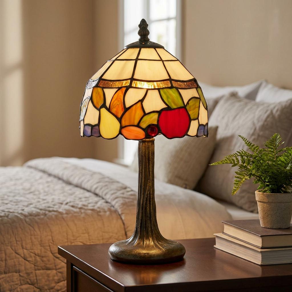Tiffany-style bedside lamp with fruit stained glass shade glowing on a wooden nightstand in a bedroom.