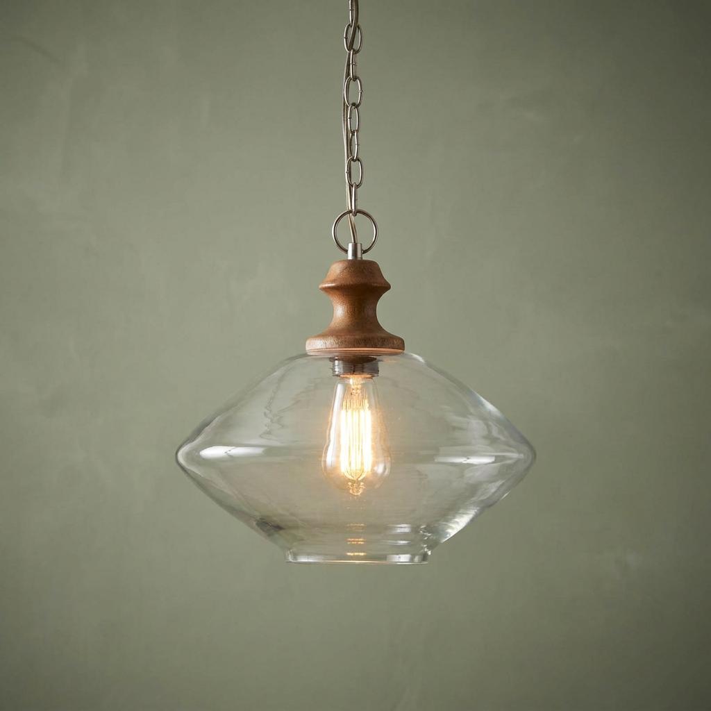 Jalpur clear glass pendant light with wood detail and Edison bulb hanging against a sage green wall.
