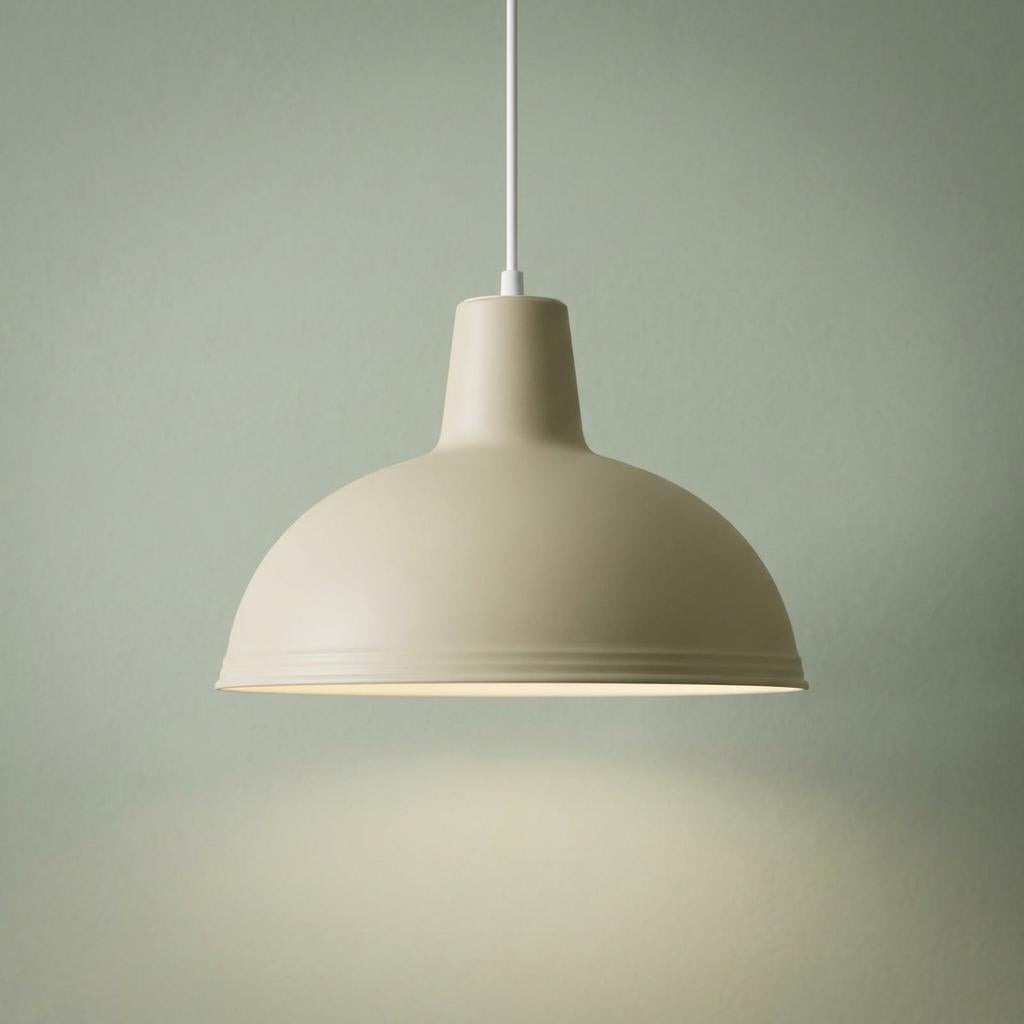 Cream dome pendant light hanging from a white cable against a pale green wall.