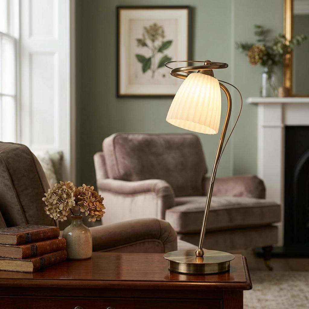 Antique brass table lamp with a pleated glass shade on a wooden table in a cozy living room setting.