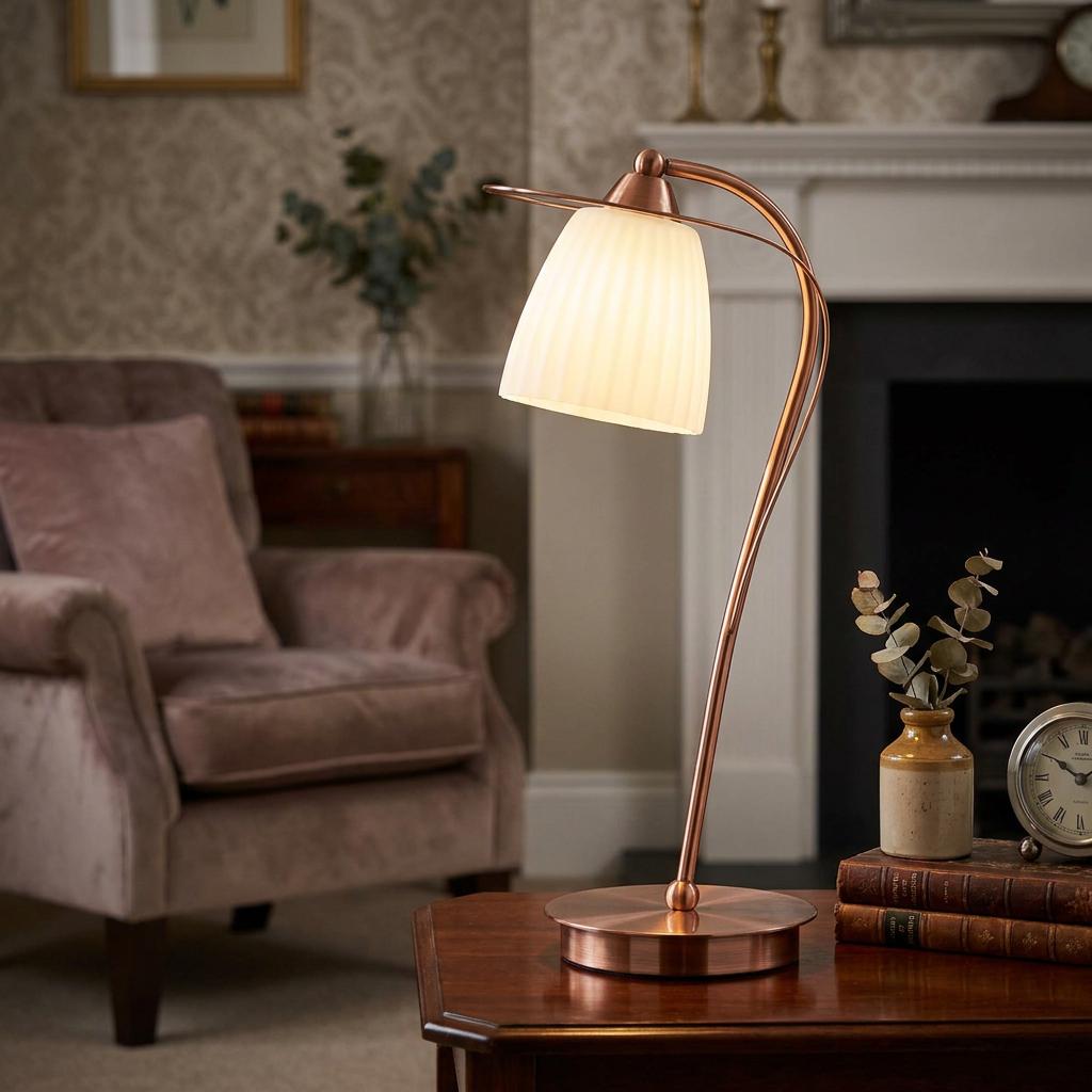 Copper table lamp with a curved stem and white ribbed glass shade on a wooden table in a cozy living room.