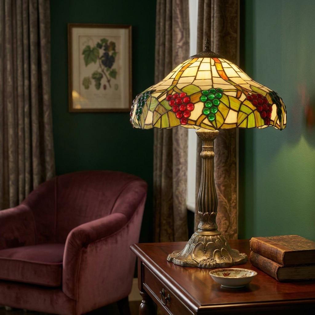 Tiffany style table lamp with a grape-patterned stained glass shade on a wooden desk in a cozy room.