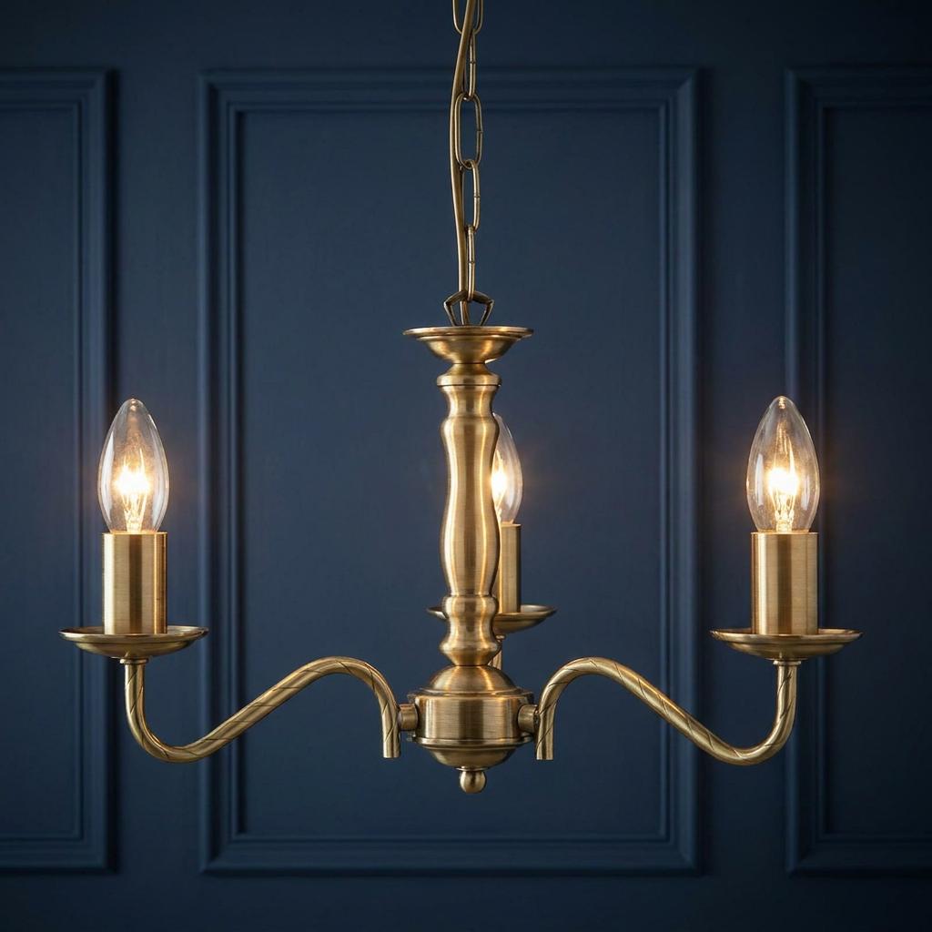 Three-light antique brass chandelier with curved arms and candle bulbs against a dark blue paneled wall.