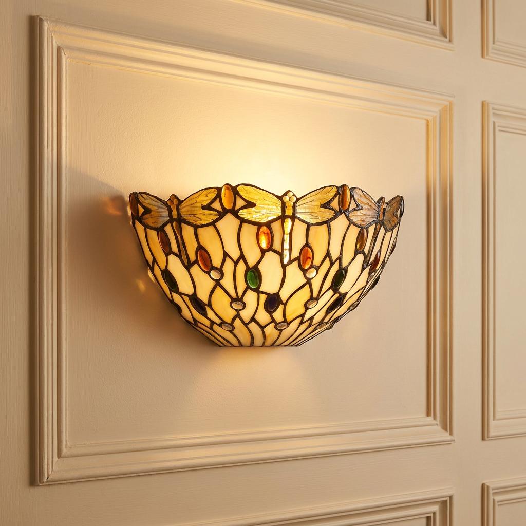 Tiffany dragonfly wall sconce with amber and green jewels mounted on a cream paneled wall.