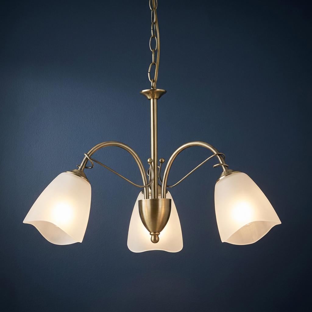 Three-light antique brass chandelier with frosted glass shades illuminated against a dark blue wall.