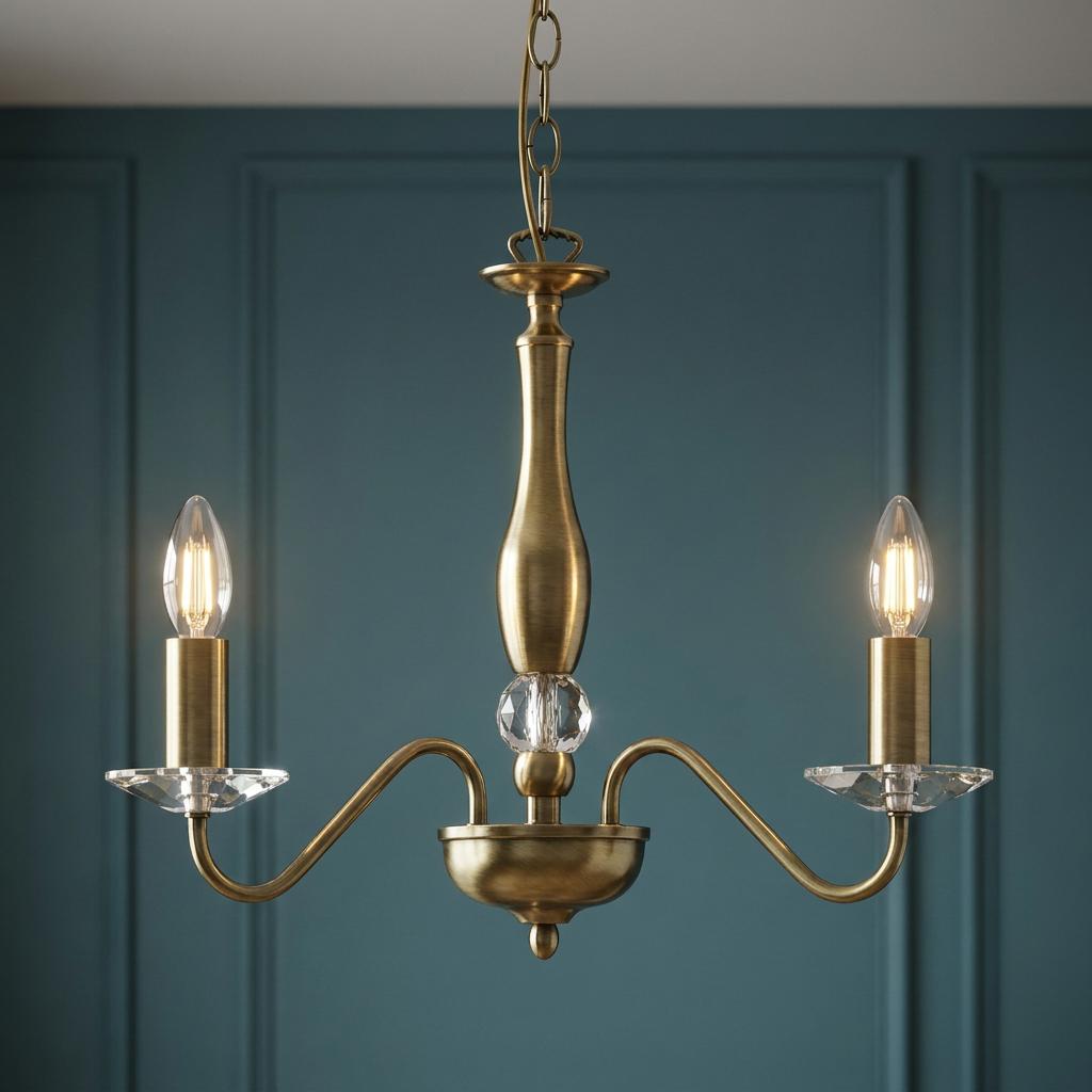 Three-light antique brass chandelier with crystal glass accents and candle-style bulbs against a teal paneled wall.