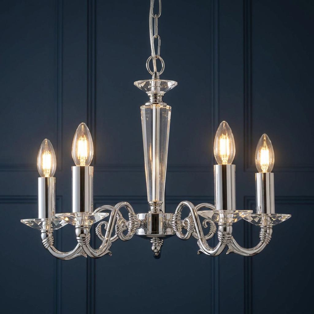 Chrome five-light chandelier with crystal details and lit candle bulbs against a dark blue paneled wall.