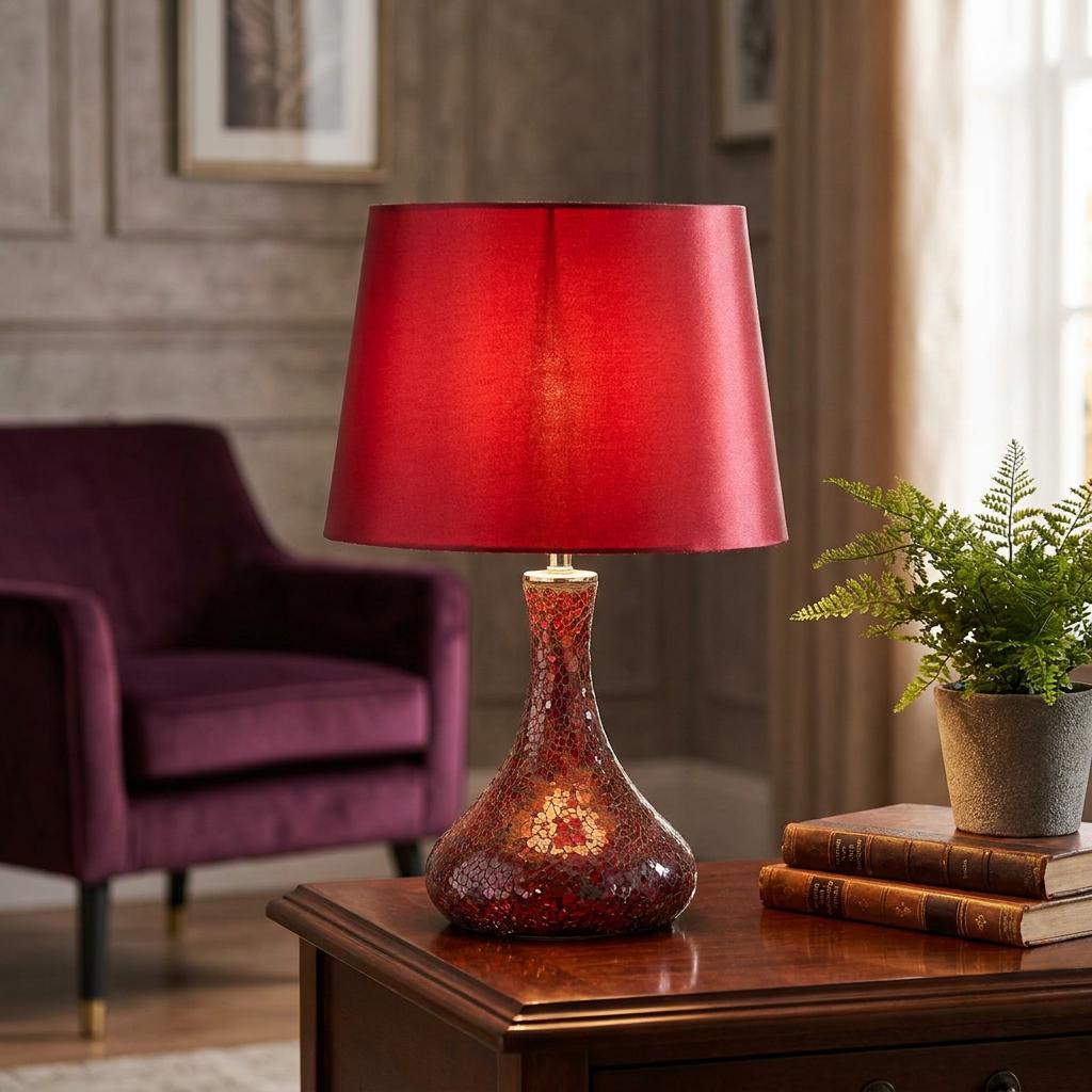 Red mirrored mosaic table lamp with a tapered red shade on a wooden table in a cozy living room setting.