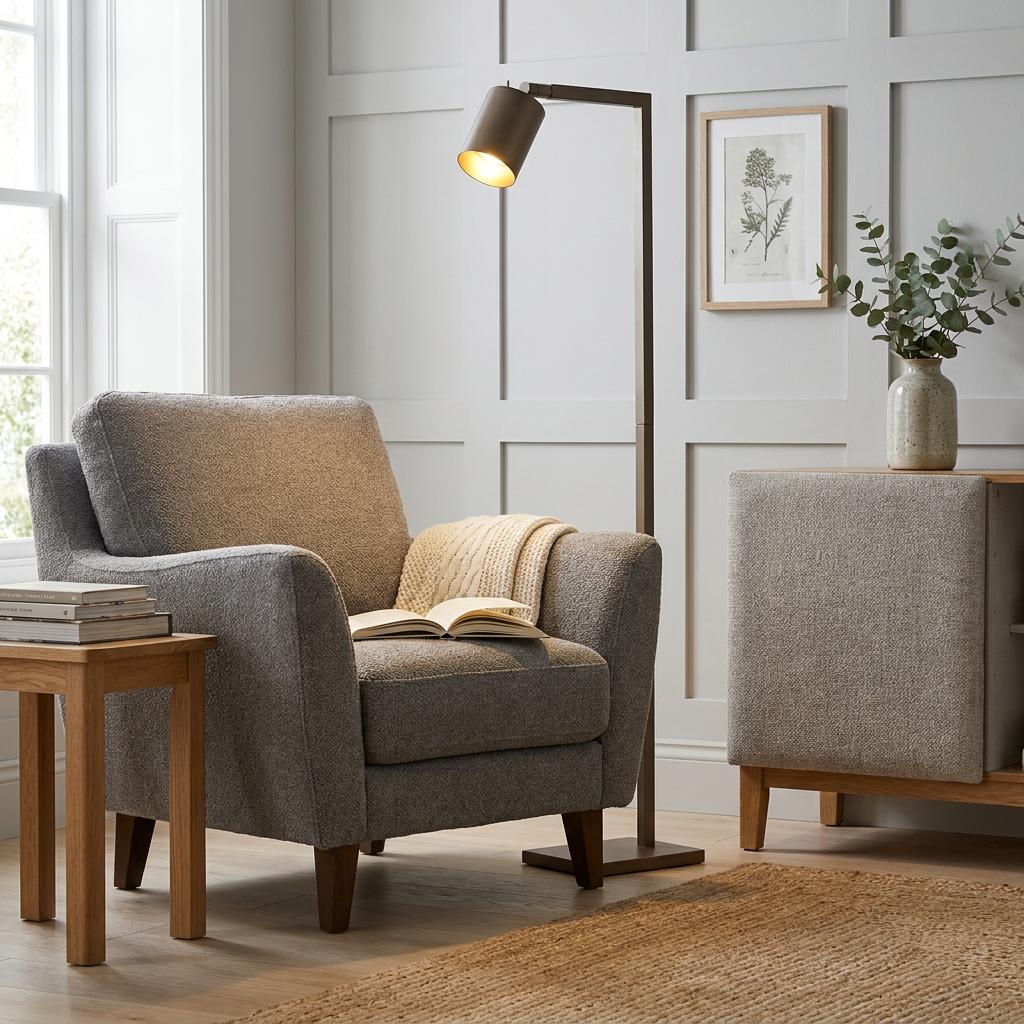 Latte metallic floor lamp with an angled head illuminating a grey armchair in a modern living room.