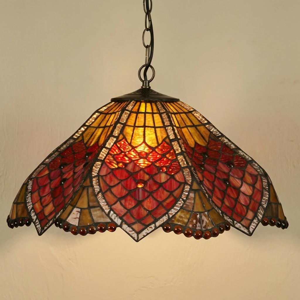 Hanging Tiffany pendant light with scalloped red and amber stained glass shade glowing against a wall.