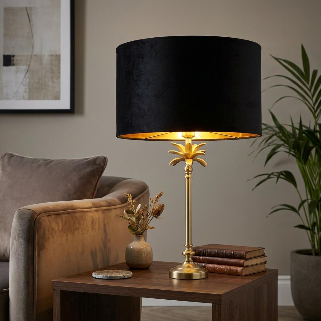 Satin brass palm table lamp with a black velvet shade on a wooden side table in a living room setting.