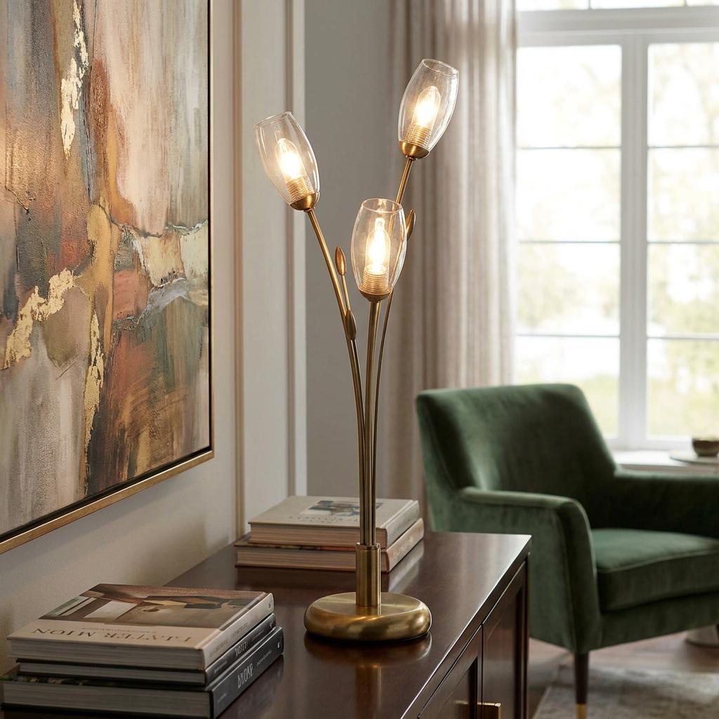 Antique brass table lamp with three branch-like stems and clear glass shades glowing on a wooden sideboard.