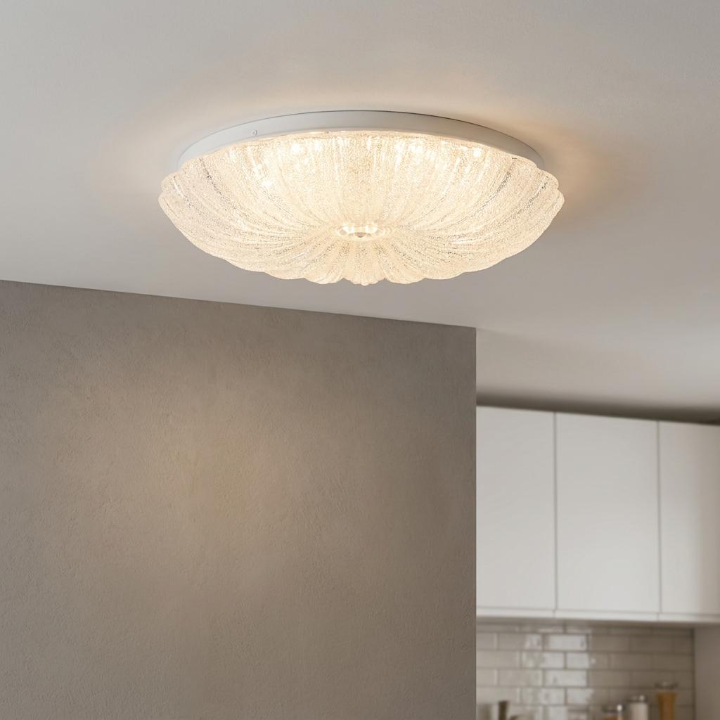A round, textured clear acrylic LED ceiling light glows softly on a white ceiling above a neutral grey wall.