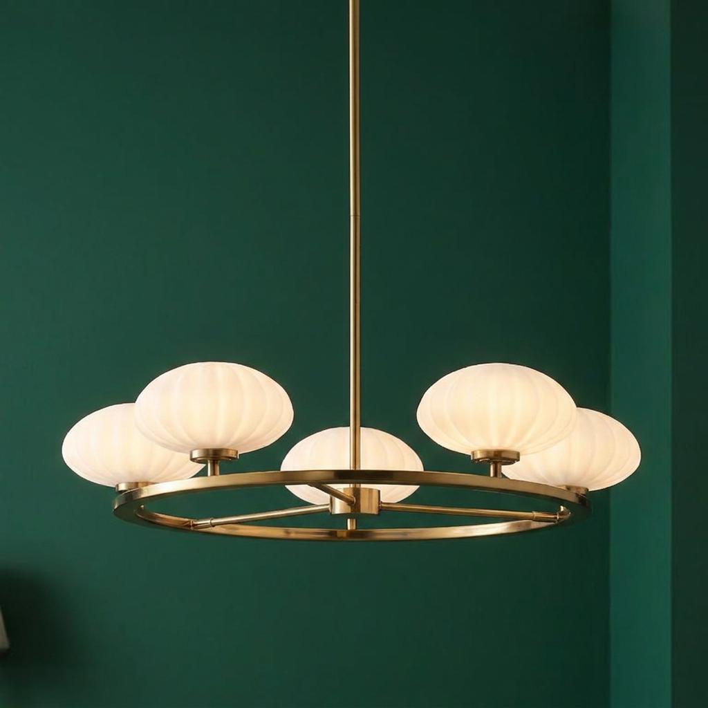 Pim 5-light gold chandelier with glowing white ribbed glass shades on a circular frame against a green wall.
