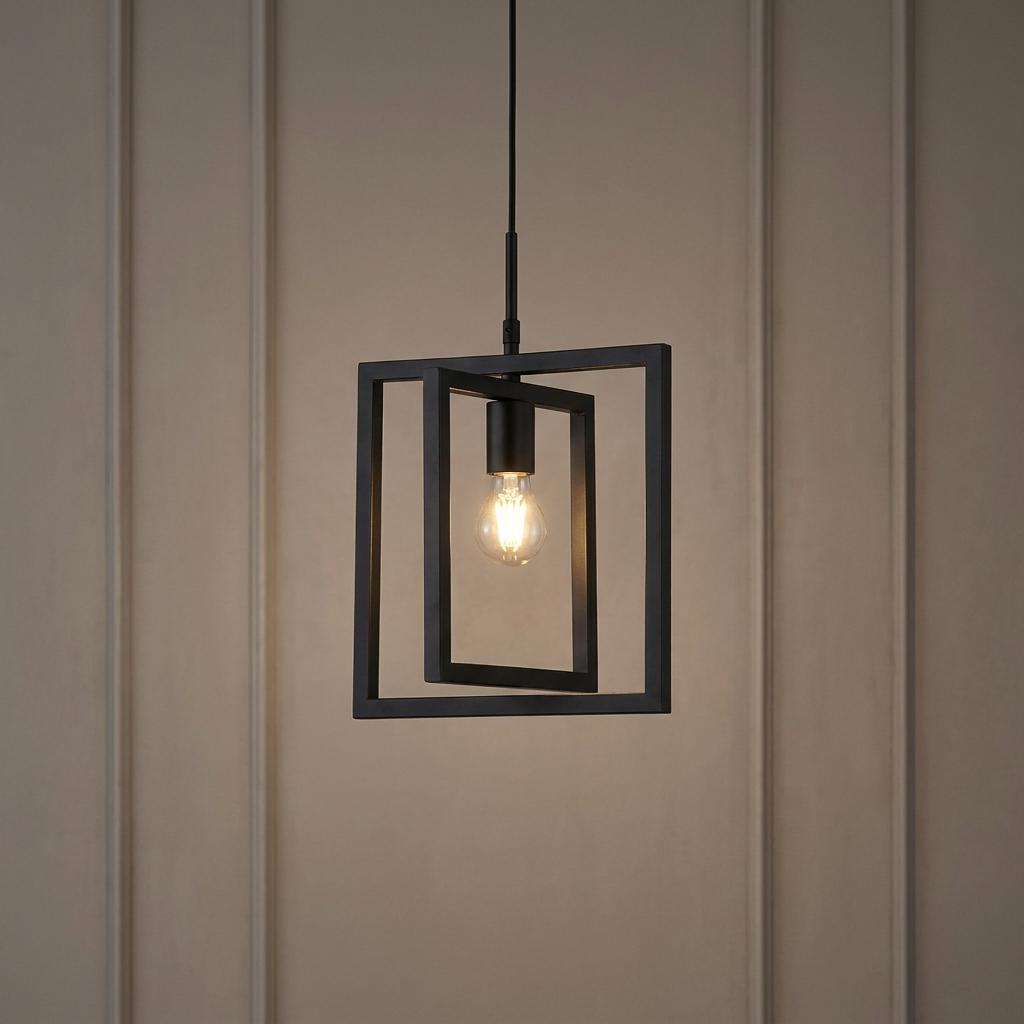Modern black metal pendant light with nested rectangular frames and a glowing bulb against a taupe paneled wall.
