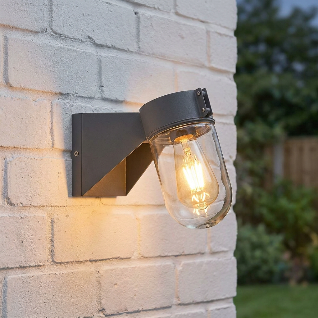 Modern grey outdoor wall lantern with a warm Edison bulb mounted on a white brick wall.