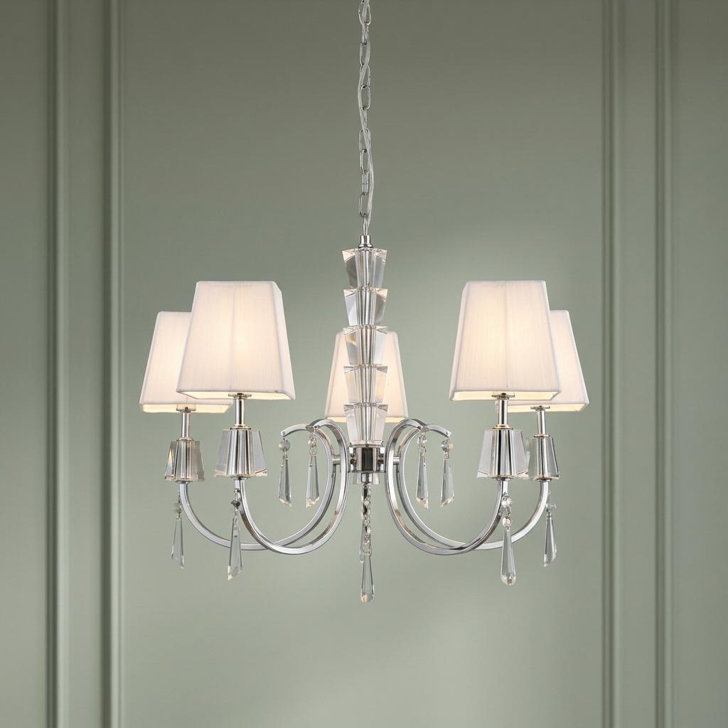 Chrome and crystal 5-light pendant chandelier with white fabric shades against a sage green wall.