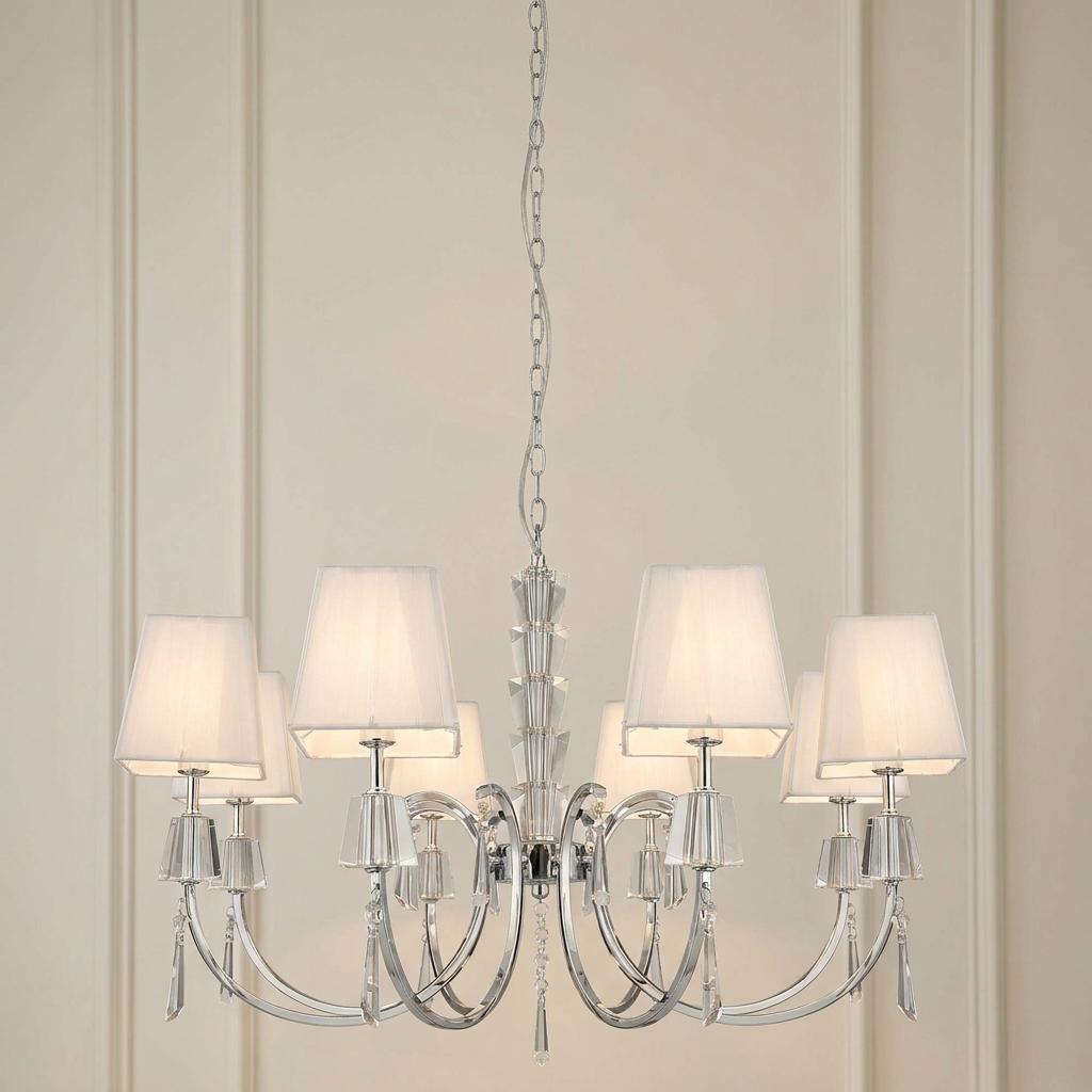 Chrome and crystal 8-light chandelier with white fabric shades against a light-colored paneled wall.