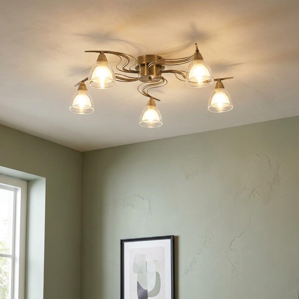 Five-light antique brass flush ceiling light with clear glass shades illuminated in a room with green walls.