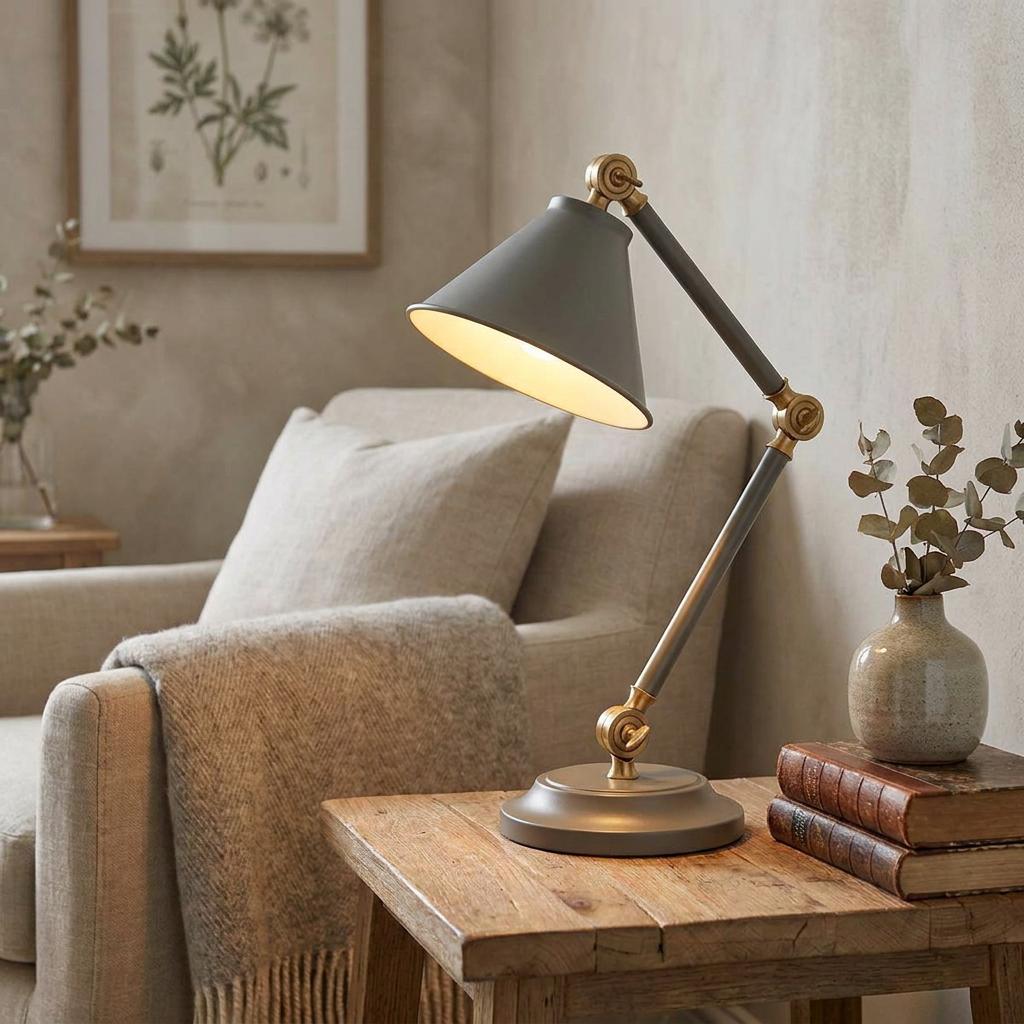A grey and aged brass mini table lamp on a wooden side table in a cozy living room setting.