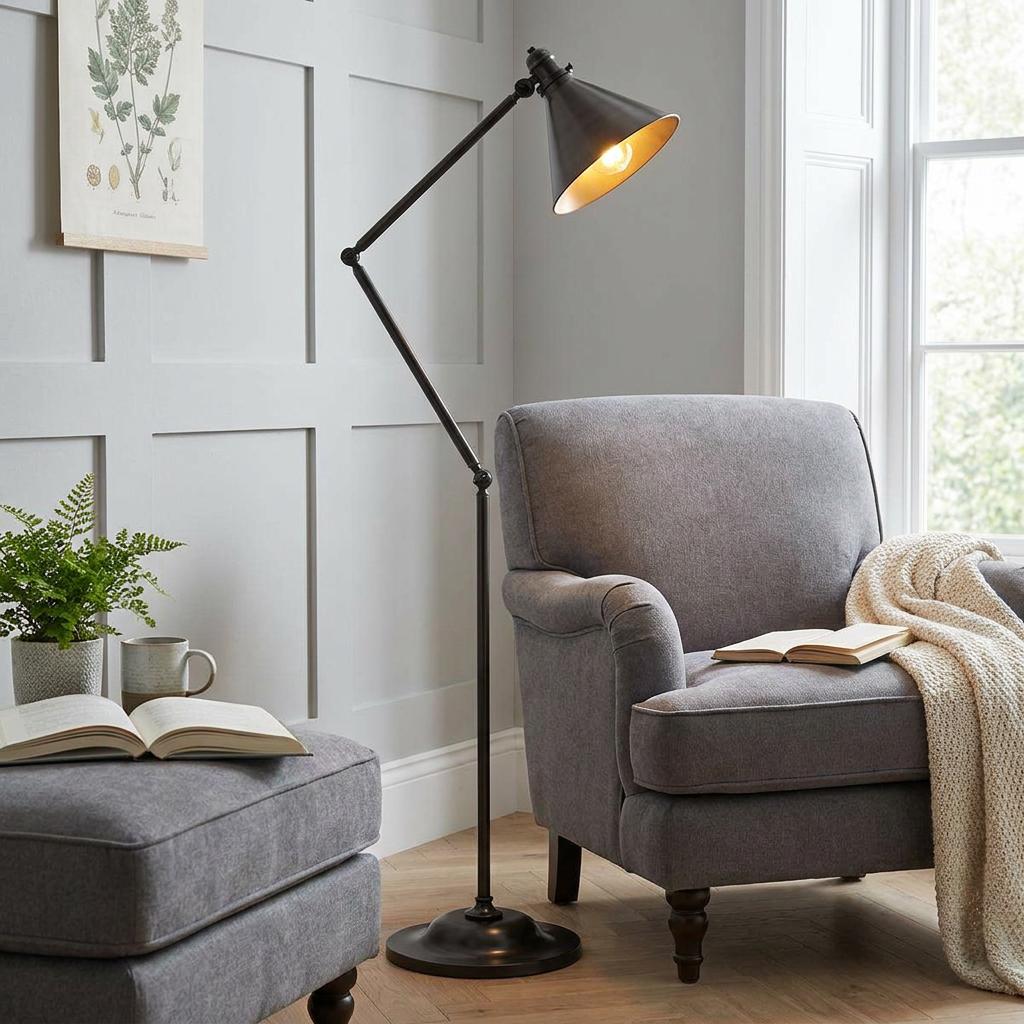 Angled Provence Old Bronze Floor Lamp with a conical shade illuminating a grey armchair in a cozy living room setting.