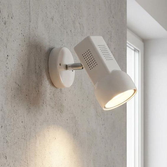White adjustable single spotlight mounted on a concrete wall, casting light onto a kitchen counter.