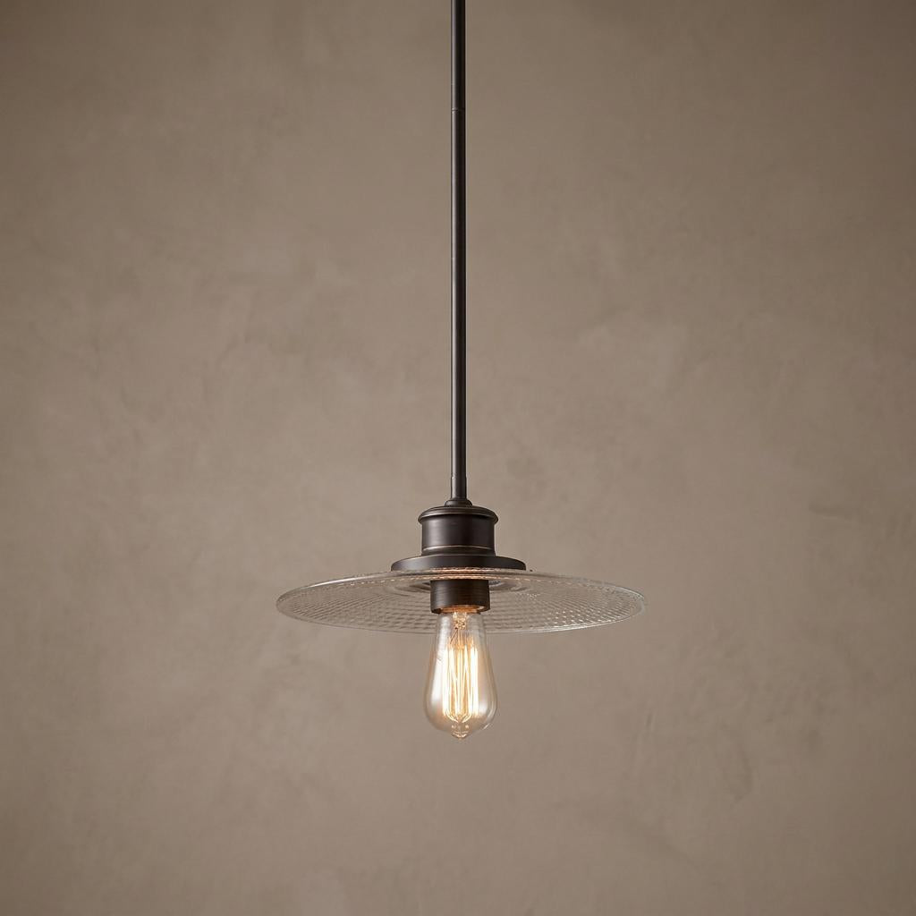 Quoizel Admiral bronze pendant light with a clear textured glass disk shade and a vintage-style bulb.