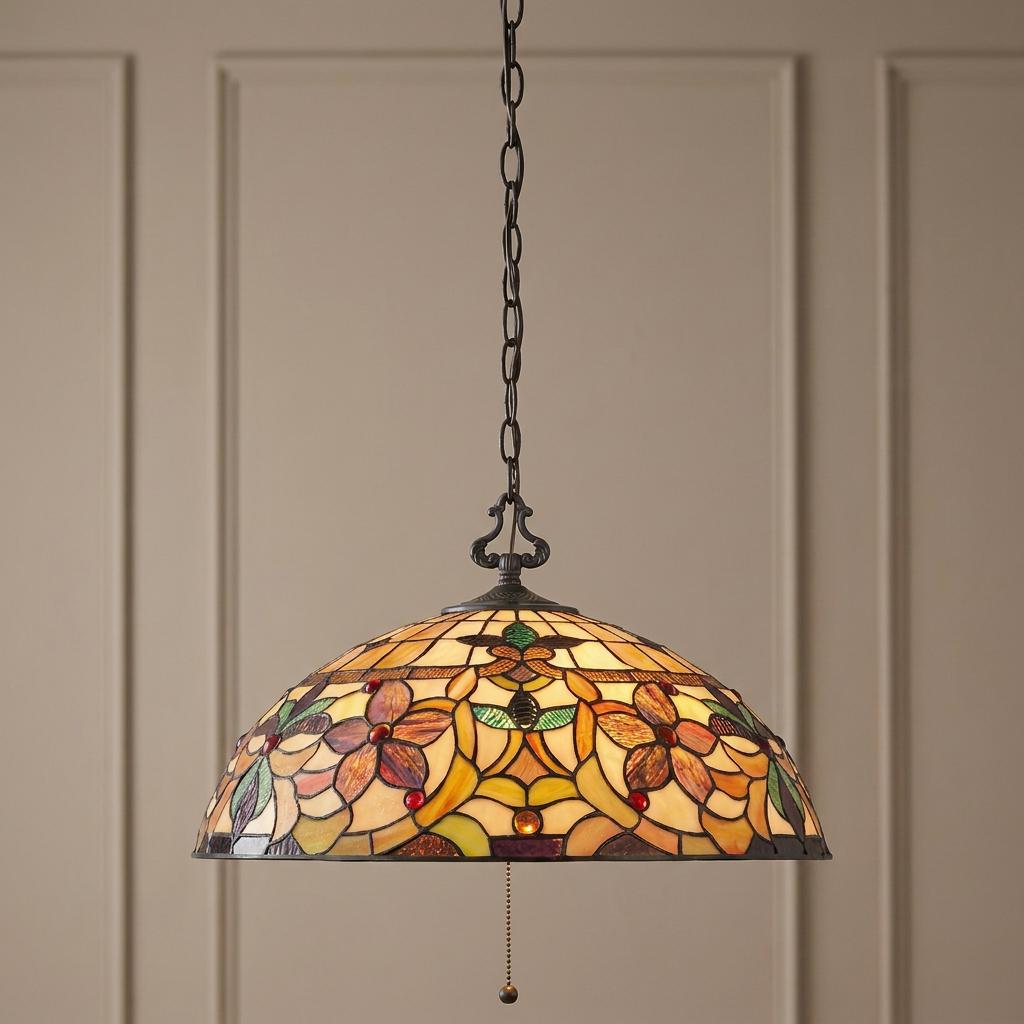 Floral stained glass pendant light with amber and green tones glowing against a neutral paneled wall.