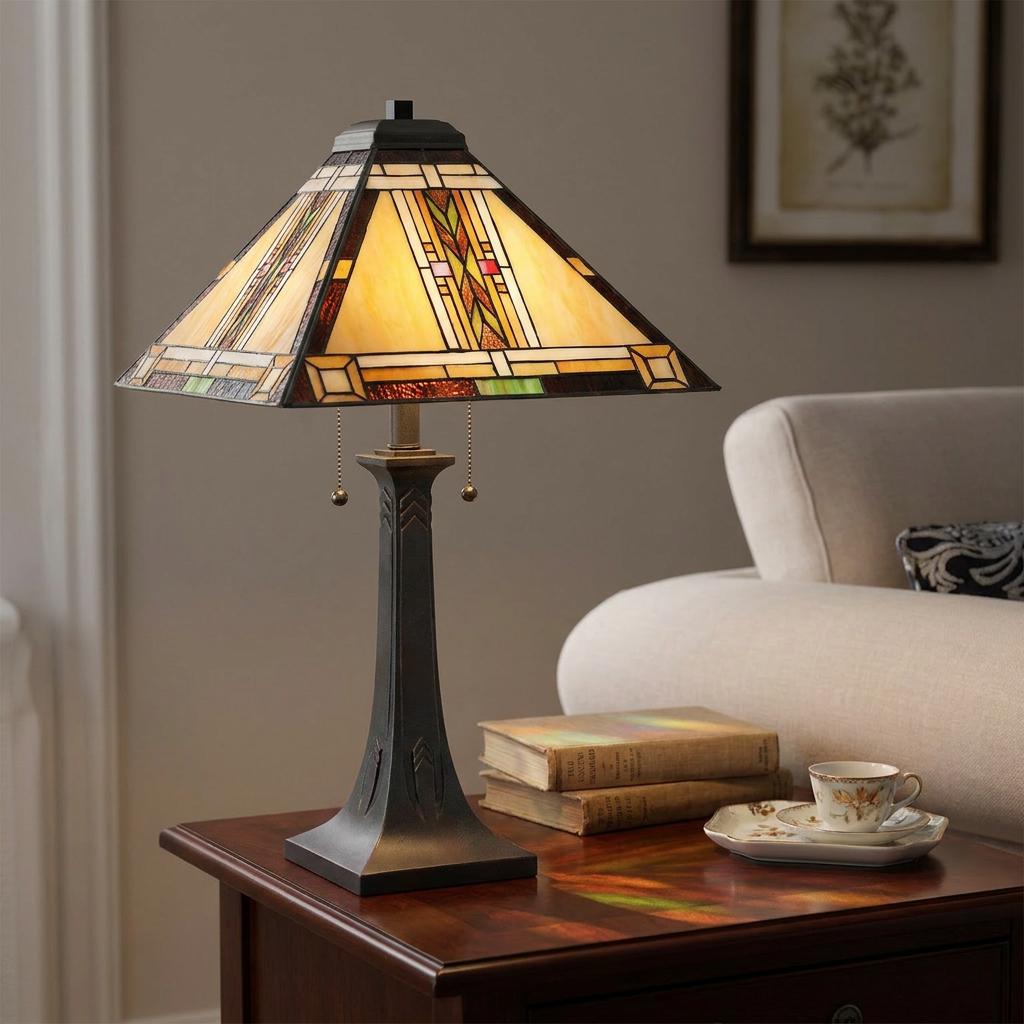 A Quoizel Navajo Tiffany table lamp with a geometric stained glass shade and bronze base glows on a living room side table.