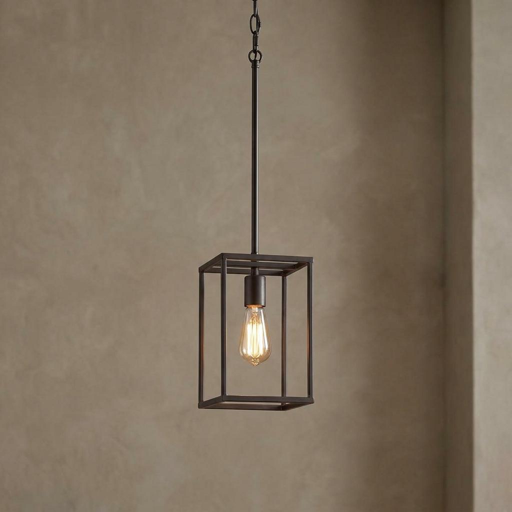 Industrial bronze cage pendant light with an exposed Edison bulb against a textured neutral wall.