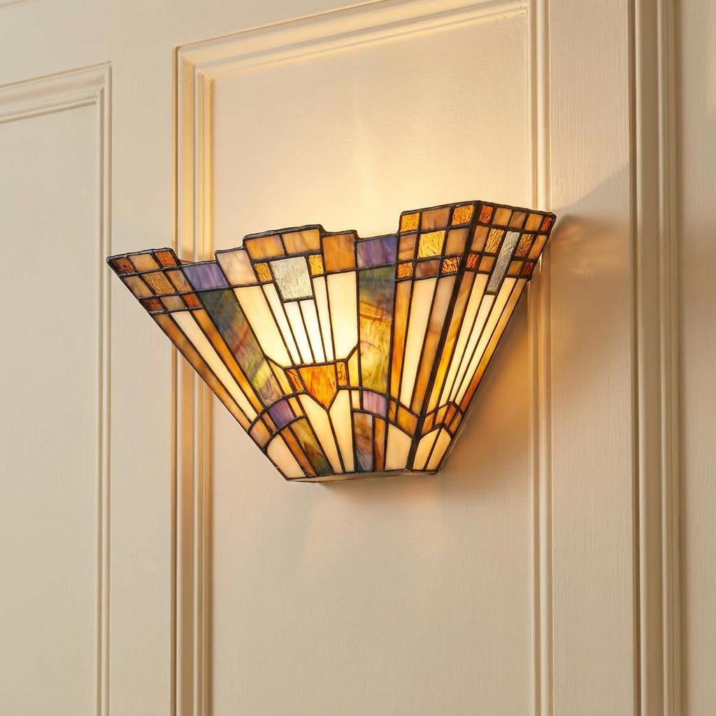 Lit Tiffany wall lamp with geometric stained glass patterns on a cream paneled wall.
