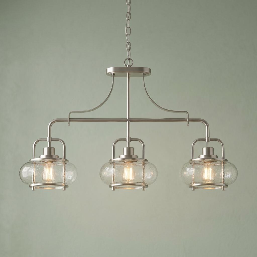 Quoizel Trilogy 3-light brushed nickel island pendant with seeded glass shades against a sage green wall.