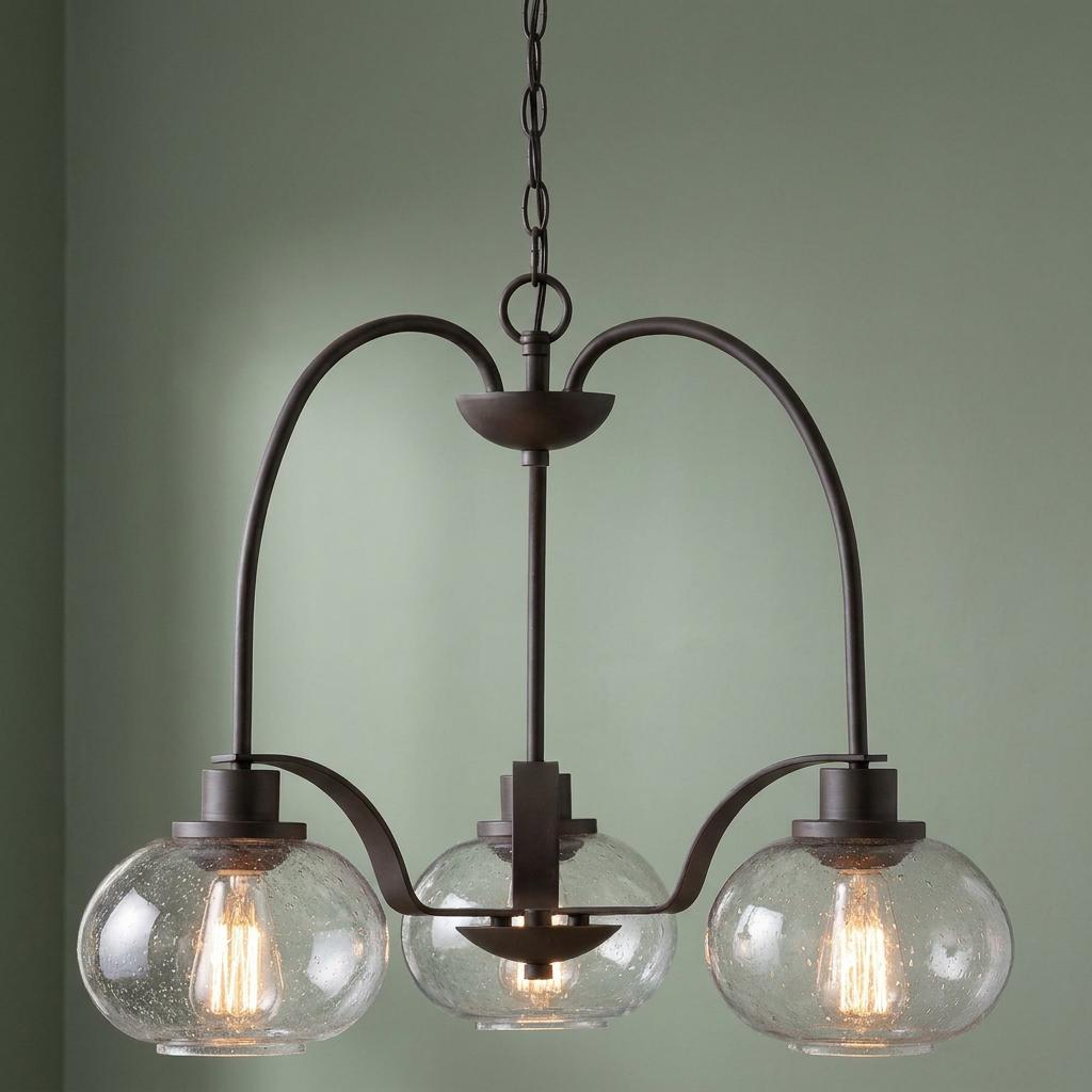 Three-light bronze chandelier with clear seeded glass globes and Edison bulbs against a pale green wall.