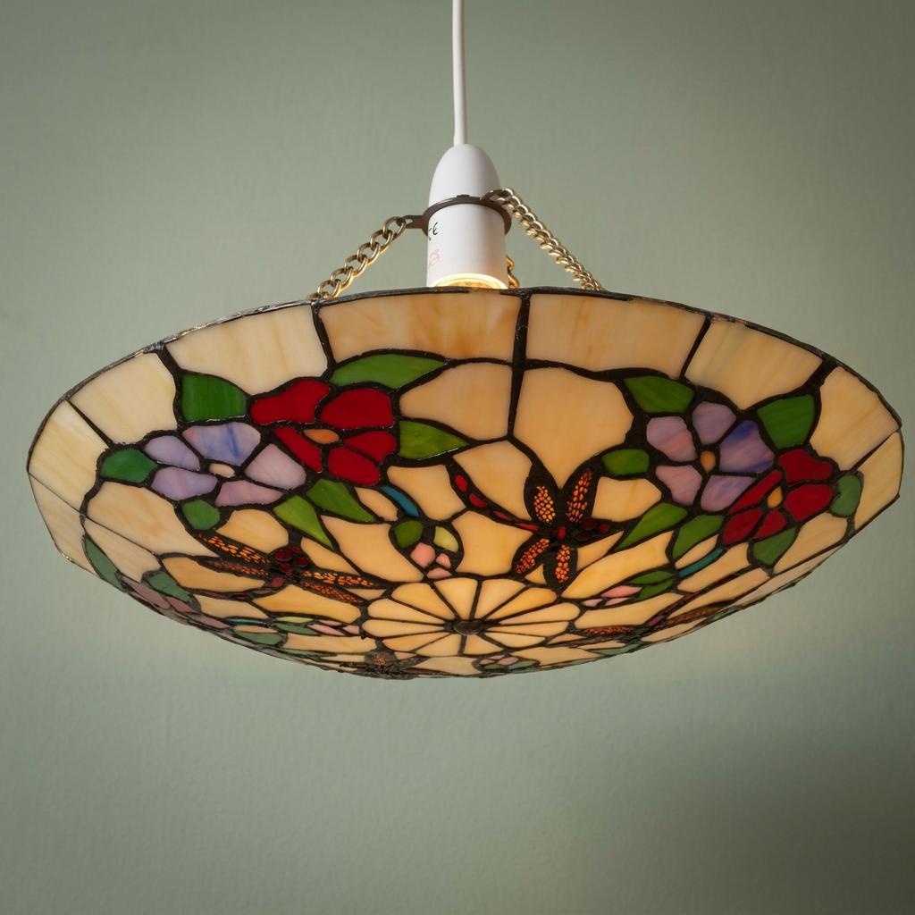 Tiffany-style ceiling lamp shade featuring red and lilac dragonflies and floral patterns against a green wall.